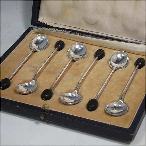 A Sterling Silver set of six tea or coffee spoons, having plain oval bowls, and handles with black coffee bean ends, all in their original cream satin and velvet-lined presentation box. Made by Mappin & Webb of Sheffield in 1925. The dimensions of this fine hand-made set of teaspoons or coffee spoons are length of each spoon 10 cms (4 inches), and the total weight is approx. 50g (1.5 troy ounces). Please note that the satin band covering the internal hinge is damaged.    