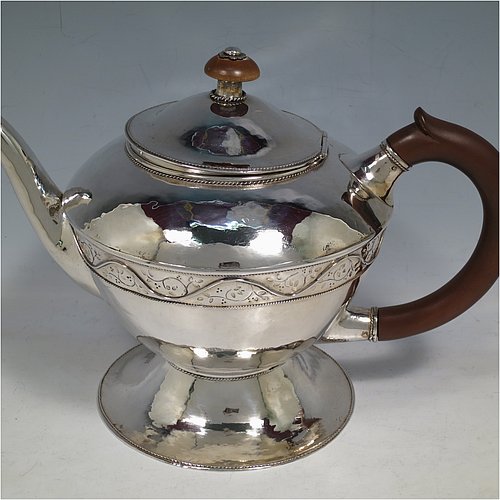 A unique Sterling Silver Arts and Crafts style three-piece tea set, having round bodies with hand-hammered decoration, with applied and hand-chased bands of floral work, the teapot with brown-stained wooden handle and finial, and the sugar and creamer with cast rounded handles, all with applied rope-twist borders, and all sitting on spreading pedestal feet. This beautiful silver tea set was made by Harold Edwin Landon of Chester in 1933. The dimensions of this fine hand-made Arts and Crafts tea service are height of teapot 18 cms (7 inches), length 28 cms (11 inches), diameter 15 cms (6 inches), and with a total weight of approx. 992g (32 troy ounces).