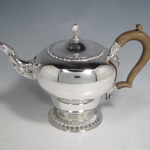 Sterling silver heavy three-piece tea set, consisting of teapot, sugar bowl, and cream jug, in a round baluster style having plain bodies, with applied gadroon borders, cast scroll handles and gold-gilt interiors, the teapot with a hinged lid and flame finial, a wooden insulated handle, and all sitting on pedestal feet with hand-chased swirl fluting. Made by Charles Townley and John Thomas, of London in 1913. The dimensions of this fine hand-made silver tea set are height of teapot 18 cms (7 inches), length 26.5 cms (10.5 inches), and it weighs a total of approx. 1,490g (48 troy ounces).    