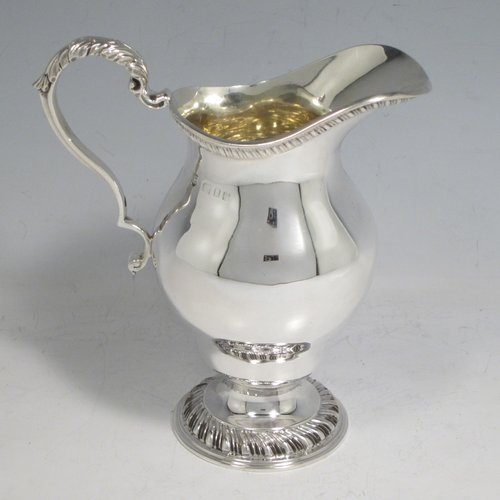 Sterling silver heavy three-piece tea set, consisting of teapot, sugar bowl, and cream jug, in a round baluster style having plain bodies, with applied gadroon borders, cast scroll handles and gold-gilt interiors, the teapot with a hinged lid and flame finial, a wooden insulated handle, and all sitting on pedestal feet with hand-chased swirl fluting. Made by Charles Townley and John Thomas, of London in 1913. The dimensions of this fine hand-made silver tea set are height of teapot 18 cms (7 inches), length 26.5 cms (10.5 inches), and it weighs a total of approx. 1,490g (48 troy ounces).    