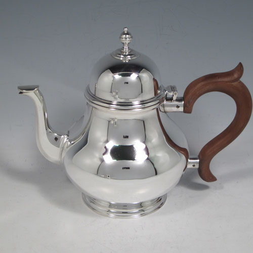 Sterling silver three-piece tea set, ccnsisting of teapot, sugar bowl, and cream jug, in a George I style having plain round baluster bodies, a hinged and domed lid, wooden insulated handle, a sparrow-beak style cream jug, and all sitting on pedestal feet. Made by Wakely and Wheeler of London in 1972. The dimensions of this fine hand-made silver tea set are height of teapot 16.5 cms (6.5 inches), length 21 cms (8.25 inches), and it weighs a total of approx. 830g (26.7 troy ounces).