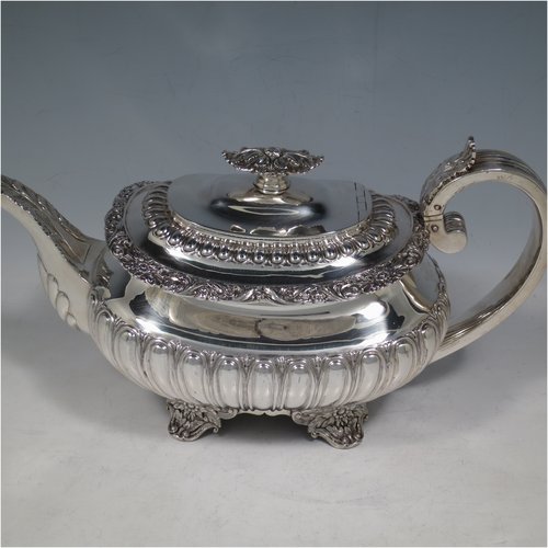 An Antique Georgian Sterling Silver three-piece Regency style tea set, having a teapot, sugar bowl and cream jug. The bodies all hand-chased with half-fluted decoration, the sugar and creamer with gold-gilt interiors, the teapot with silver handle and finial, and an invisibly hinged lid, all with applied cast acanthus leaf and floral borders, and all sitting on four floral cast flange feet. Made by Joseph Angell of London in 1824. The dimensions of this fine hand-made antique silver tea service are length of teapot 30.5 cms (12 inches), height 16 cms (6.3 inches), and it weighs a total of approx. 1,395g (45 troy ounces).   