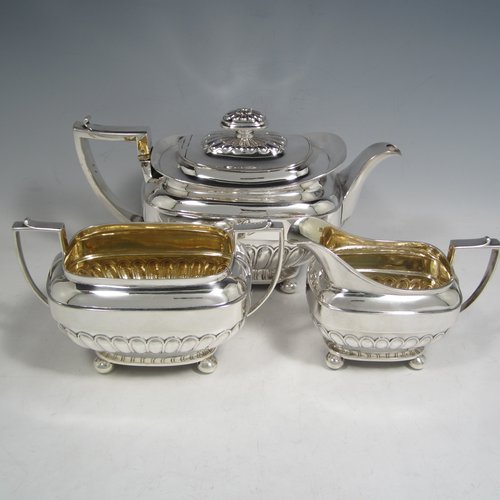 Antique Georgian sterling silver three-piece Regency style tea set, having a teapot, sugar bowl and cream jug. The bodies all hand-chased with half-fluted decoration, the sugar and creamer with gold-gilt interiors, the teapot with silver handle and finial, and an invisibly hinged lid, and all sitting on four ball feet. Made by Rebecca Emes and Edward Barnard of London in 1811 and 1813. The dimensions of this fine hand-made silver tea service are length of teapot 27 cms (10.5 inches), height 16 cms (6.3 inches), and it weighs a total of approx. 1,262g (41 troy ounces).    