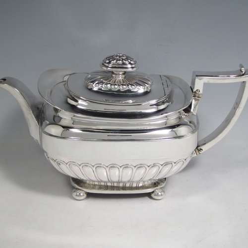 Antique Georgian sterling silver three-piece Regency style tea set, having a teapot, sugar bowl and cream jug. The bodies all hand-chased with half-fluted decoration, the sugar and creamer with gold-gilt interiors, the teapot with silver handle and finial, and an invisibly hinged lid, and all sitting on four ball feet. Made by Rebecca Emes and Edward Barnard of London in 1811 and 1813. The dimensions of this fine hand-made silver tea service are length of teapot 27 cms (10.5 inches), height 16 cms (6.3 inches), and it weighs a total of approx. 1,262g (41 troy ounces).    