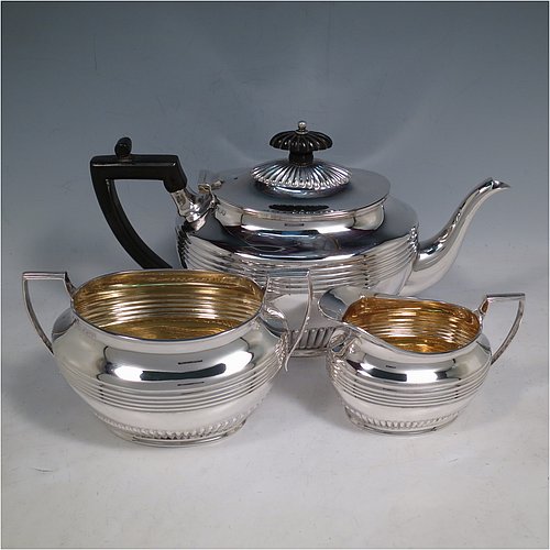 An elegant Antique Victorian Sterling Silver three-piece tea set, having oval shaped bodies, with fine half-fluted and reeded hand-chased decoration, reeded handles on the sugar & cream jug together with gold-gilt interiors, and a wooden handle & finial on the teapot, and all sitting on collet foot bases. This handsome silver tea service was made by Henry Stratford of Sheffield in 1900. The dimensions of this fine hand-made antique silver tea set are length of teapot 28 cms (11 inches), height 15 cms (6 inches), and the total weight is approx. 775g (25 troy ounces).    