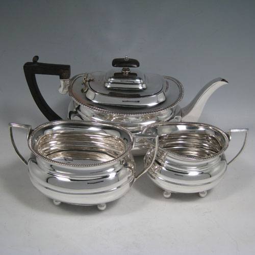 A handsome Antique Sterling silver three-piece tea and coffee set, having plain baluster bodies, applied gadroon borders, the teapot with hinged lid, wooden finial and handle, and all sitting on four ball feet. This elegant silver tea set was made by William Hutton of Sheffield in 1918. The dimensions of this fine hand-made antique silver tea service are length of teapot 29 cms (11.5 inches), height 15 cms (6 inches), and the total weight is approx. 1,147g (37 troy ounces).