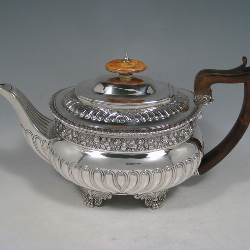 Antique Georgian sterling silver three-piece Regency style tea set, having a teapot, sugar bowl and cream jug. The bodies all hand-chased with roses and converging flute decoration, with applied gadroon borders, the sugar and creamer with gold-gilt interiors, the teapot with wooden handle and ivory finial, and an invisibly hinged lid, and all sitting on four cast foliate feet. Made by Charles Fox I of London in 1821. The dimensions of this fine hand-made silver tea service are length of teapot 29 cms (11.5 inches), height 17 cms (6.75 inches), and it weighs a total of approx. 1,260g (41 troy ounces). 