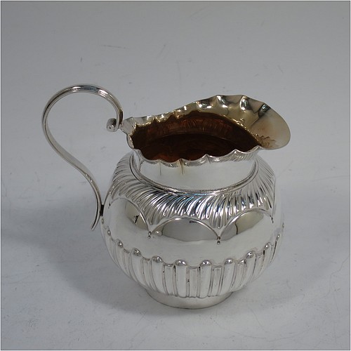 A very pretty Antique Victorian Sterling Silver three-piece bachelor tea set, having round bellied bodies with beautiful bands of hand-chased fluted decoration and wavy top borders, the teapot with a hinged lid and wooden finial, a wooden scroll handle, and the cream and sugar bowl with gold-gilt interiors, all sitting on collet feet. Made by Thomas Hayes of Birmingham in 1888. The dimensions of this fine hand-made antique silver bachelor tea set are height of teapot 14 cms (5.5 inches), length of teapot 19 cms (7.5 inches), with a total weight of approx. 474g (15.3 troy ounces).    