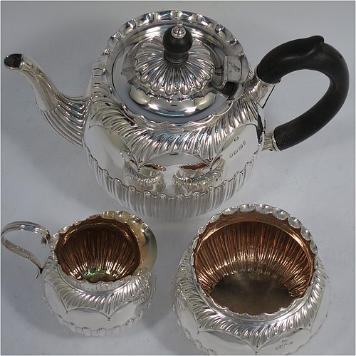 A very pretty Antique Victorian Sterling Silver three-piece bachelor tea set, having round bellied bodies with beautiful bands of hand-chased fluted decoration and wavy top borders, the teapot with a hinged lid and wooden finial, a wooden scroll handle, and the cream and sugar bowl with gold-gilt interiors, all sitting on collet feet. Made by Thomas Hayes of Birmingham in 1888. The dimensions of this fine hand-made antique silver bachelor tea set are height of teapot 14 cms (5.5 inches), length of teapot 19 cms (7.5 inches), with a total weight of approx. 474g (15.3 troy ounces).    