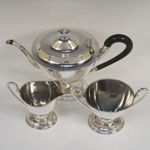 A very handsome Antique Edwardian Sterling Silver three-piece tea set, in a neoclassical style having plain oval shaped bodies, with loop side-handles, a wooden handle and finial on the teapot, and all sitting on oval pedestal feet. This elegant antique silver tea set was all made by Walker and Hall of Sheffield in 1908. The dimensions of this fine hand-made antique silver tea set are length of teapot 24 cms (9.5 inches), height 18.5 cms (7.25 inches), and the total weight is approx. 775g (25 troy ounces).   