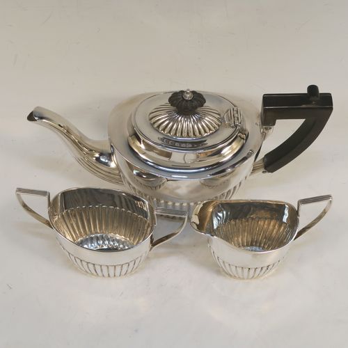 A handsome Antique Sterling Silver Bachelor three-piece tea set, having oval shaped bodies, with half-fluted hand-chased decoration, with reeded handles on the sugar & cream jug, a wooden handle and finial on the teapot, and all sitting on flat bases. This beautiful antique silver bachelor tea set was all made by John Milward Banks of Birmingham in 1896. The dimensions of this fine hand-made antique silver bachelor tea set are length of teapot 21.5 cms (8.5 inches), height 12.5 cms (5 inches), and the total weight is approx. 320g (10.3 troy ounces).  