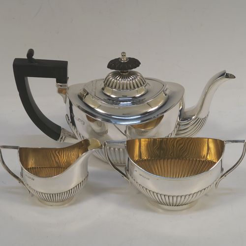 A pretty Antique Sterling Silver Bachelor three-piece tea set, having oval shaped bodies, with half-fluted hand-chased decoration, gold-gilt interiors and reeded handles on the sugar & cream jug, a wooden handle and finial on the teapot, and all sitting on flat bases. This beautiful antique silver bachelor tea set was all made by Albert Bloxham of London and Birmingham in 1908 and 1913. The dimensions of this fine hand-made antique silver bachelor tea set are length of teapot 21.5 cms (8.5 inches), height 12 cms (4.75 inches), and the total weight is approx. 300g (9.7 troy ounces).   