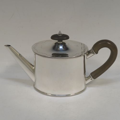 A very pretty Sterling Silver three-piece bachelor sized tea set, consisting of a teapot, sugar bowl, and cream jug, in a plain oval style with straight sides and applied bead-edged borders, the teapot with a brown wooden handle, finial, and a hinged domed lid with a flat invisible hinge, the sugar and creamer with scroll handles, and all sitting on flat bases. This beautiful silver bachelor size three-piece tea set was made by Roberts and Belk of Sheffield in 1940. The dimensions of this fine hand-made silver tea set are height of teapot 11.5 cms (4.5 inches), length 21.5 cms (8.5 inches), and it weighs a total of approx. 450g (14.5 troy ounces).  