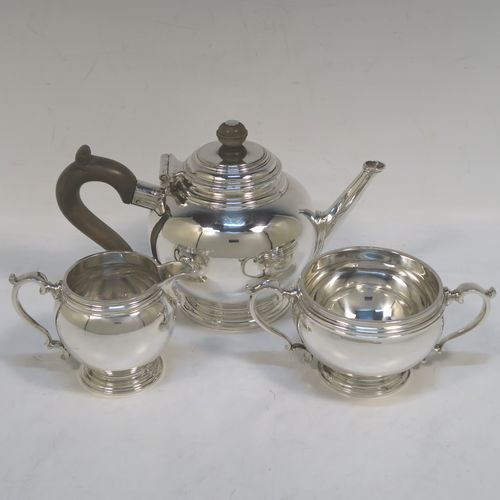 A heavy and very handsome Sterling Silver Bachelor three-piece tea set, having plain round bellied shaped bodies with reeded borders, the cream jug and sugar bowl with cast scroll side-handles, the teapot with a wooden handle and finial, and all sitting on round pedestal feet. This elegant silver bachelor tea set was all made by Robert Comyns of London in 1929. The dimensions of this fine hand-made and heavy silver bachelor tea set are length of teapot 20.5 cms (8 inches), height 11.5 cms (4.5 inches), and the total weight is approx. 807g (26 troy ounces).   