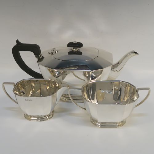 A very handsome Sterling Silver Art Deco style  three-piece tea set, consisting of a teapot, sugar bowl, and cream jug, having plain panelled bodies and angular handles, the teapot with a black wooden handle, finial, and a hinged lid, and all sitting on collet feet. This elegant silver tea set was made by the Cooper Brothers of Sheffield in 1966. The dimensions of this fine hand-made Art Deco style silver tea set are height of teapot 13.5 cms (5.3 inches), length 28 cms (11 inches), and it weighs a total of approx. 1,062g (34 troy ounces).   