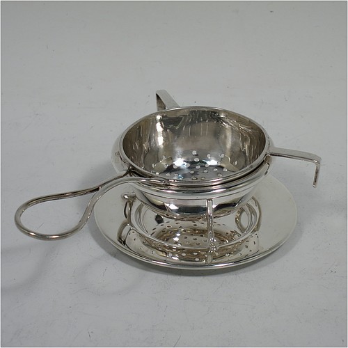 A very stylish Sterling Silver tea strainer and stand, having a round hand-pierced bowl, with wire-work loop handle and two right-angled cup supports, all sitting on an original plain round dregs stand with a wire-work galleried holder on flat base. Made by James Round of Sheffield in 1921. The dimensions of this fine hand-made silver tea strainer and stand are height 4 cms (1.5 inches), length over handle 12 cms (4.75 inches), and it weighs a total of approx. 68g (2.2 troy ounces). 