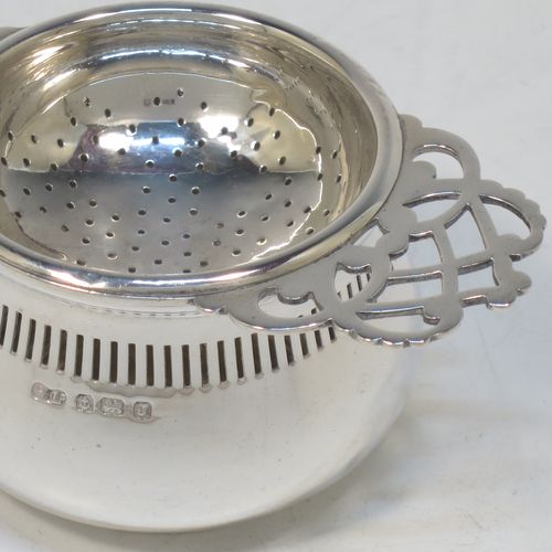 A pretty Sterling Silver tea strainer and bowl, having a hand-pierced handle, a round hand-pierced bowl with hand-cut side holder, and sitting on a plain round dregs stand with a band of piercing and bellied sides. Made by William Suckling Ltd., of Birmingham in 1933. The dimensions of this fine hand-made silver tea strainer & stand are length 14.5 cms (5.75 inches), diameter of stand 6 cms (2.3 inches), with a total weight of approx. 75g (2.4 troy ounces).  