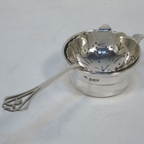 A very pretty Sterling Silver tea strainer and bowl, having a floral hand-pierced handle, a round hand-pierced bowl with two side holder lugs, and sitting on a plain round dregs bowl with a hand-chased middle band. Made by Frances Howard of Sheffield in 1923. The dimensions of this fine hand-made silver tea strainer & bowl are length 15 cms (6 inches), diameter of bowl 6.5 cms (2.5 inches), with a total weight of approx. 87g (2.8 troy ounces).   