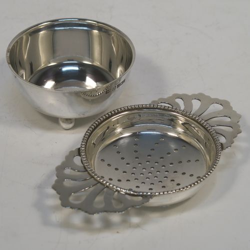 An elegant Sterling Silver tea strainer and dregs bowl in a Georgian lemon strainer style, having a round hand-pierced bowl with an applied bead-edged border, with two hand-pierced side-handles, and sitting on an original plain round dregs stand with three ball feet. This beautiful silver tea strainer was made by Hampton Utilities of Birmingham in 1965. The dimensions of this fine hand-made silver tea strainer and bowl are height 3.5 cms (1.3 inches), width across handles 11 cms (4.25 inches), diameter of bowl 6.5 cms (2.5 inches), and it weighs a total of approx. 87g (2.8 troy ounces).   