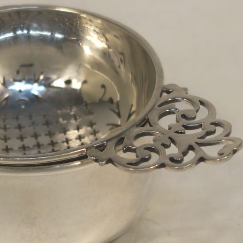 A handsome Sterling Silver tea strainer and dregs bowl in a Georgian lemon strainer style, having a round hand-pierced bowl, with two hand-pierced side-handles, and sitting on an original plain round dregs stand with a flat base. Made by Mappin and Webb of Birmingham in 1930. The dimensions of this fine hand-made silver tea strainer and bowl are height 4 cms (1.5 inches), width across handles 12 cms (4.75 inches), and it weighs a total of approx. 86g (2.8 troy ounces).  