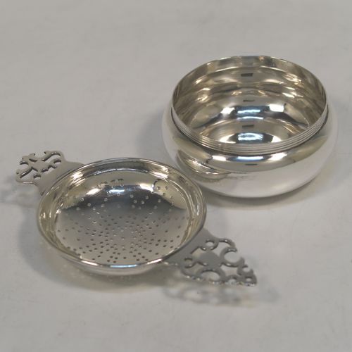 A handsome Sterling Silver tea strainer and dregs bowl in a Georgian lemon strainer style, having a round hand-pierced bowl, with two hand-pierced side-handles, and sitting on an original plain round dregs stand with a reeded border and flat base. This elegant silver tea strainer and bowl was made by Robert Comyns of London in 1940. The dimensions of this fine hand-made silver tea strainer and bowl are height 3.5 cms (1.3 inches), length across handles 12 cms (4.75 inches), and it weighs a total of approx. 80g (2.6 troy ounces).   