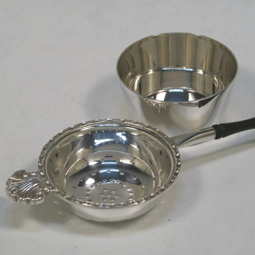 A very pretty Sterling Silver tea strainer and bowl, having a plain black stained wood-turned handle, a round hand-pierced bowl with an applied floral border and a cast shell side holder, and sitting on a plain round dregs bowl with a flat base. This beautiful silver tea strainer and bowl were made by Francis Howard of Sheffield in 1984. The dimensions of this fine hand-made silver tea strainer & bowl are length 18 cms (7 inches), diameter of bowl 6.5 cms (2.5 inches), and with a total weight of approx. 90g (3 troy ounces).  