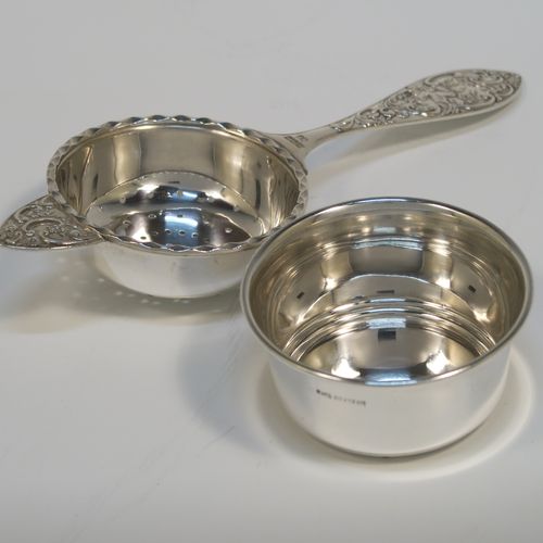 A very pretty Sterling Silver tea strainer and bowl, having a round hand-pierced strainer with an applied wavy-edged border, with a cast side-handle having floral and scroll decoration, and sitting on its original plain round bowl with straight sides and flat base. This beautiful silver tea strainer and bowl was made by John Rose of Birmingham in 1962. The dimensions of this fine hand-made silver tea strainer and bowl are length 15.5 cms (6 inches), diameter of bowl 6 cms (2.3 inches), and with a total weight of approx. 83g (2.7 troy ounces).   