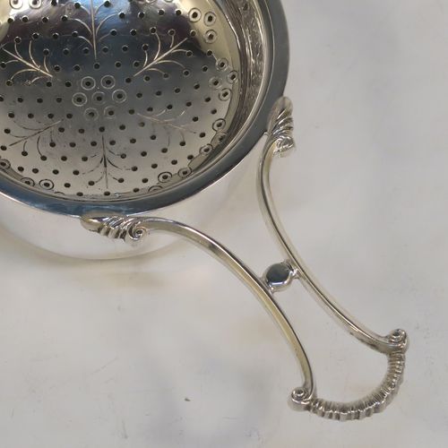 A very pretty Sterling Silver tea strainer and bowl, having a cast scroll side-handle, a round hand-pierced and engraved bowl, and sitting on a plain round dregs bowl. This elegant silver tea strainer and bowl made by Suckling Ltd. of Birmingham in 1958. The dimensions of this fine hand-made silver tea strainer & bowl are length 14 cms (5.5 inches), diameter of bowl 7 cms (2.75 inches), with a total weight of approx. 87g (2.8 troy ounces).   