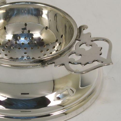 A handsome Sterling Silver tea strainer and dregs bowl, having a round hand-pierced bowl, with two hand-pierced side-handles, and sitting on an original plain round dregs stand. This elegant silver tea strainer and bowl was made by Larson Ltd. of Birmingham in 1957. The dimensions of this fine hand-made silver tea strainer and dregs stand are height 3 cms (1.25 inches), diameter of dregs stand 8 cms (3.25 inches), and it weighs a total of approx. 63g (2 troy ounces).   