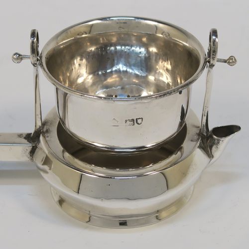 A very unusual Antique Edwardian Sterling Silver gimble-mounted tea strainer on a teapot style stand, having a round hand-pierced bowl mounted on two side stands, all sitting on an original plain round dregs stand in the shape of a teapot, together with an original wooden insulated side-handle. This rare antique silver tea strainer and stand was made by Fredericks Ltd., of London in 1907. The dimensions of this fine hand-made antique silver tea strainer and stand are height 5.5 cms (2.25 inches), length including handle 17 cms (6.75 inches), and it weighs a total of approx. 50g (1.6 troy ounces).   