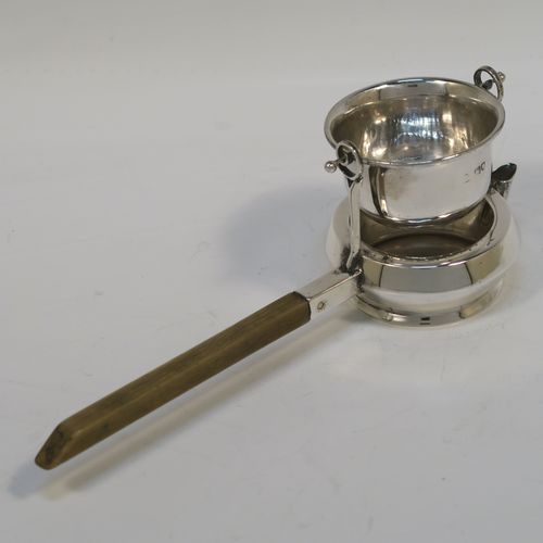 A very unusual Antique Edwardian Sterling Silver gimble-mounted tea strainer on a teapot style stand, having a round hand-pierced bowl mounted on two side stands, all sitting on an original plain round dregs stand in the shape of a teapot, together with an original wooden insulated side-handle. This rare antique silver tea strainer and stand was made by Fredericks Ltd., of London in 1907. The dimensions of this fine hand-made antique silver tea strainer and stand are height 5.5 cms (2.25 inches), length including handle 17 cms (6.75 inches), and it weighs a total of approx. 50g (1.6 troy ounces).   