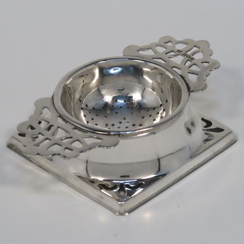 A handsome Sterling Silver tea strainer and dregs bowl, having a Georgian lemon strainer style round hand-pierced bowl, with two hand-pierced side-handles, and sitting on an original plain round dregs stand with a square base. This elegant silver tea strainer and bowl was made by Thomas Bishton of Birmingham in 1944. The dimensions of this fine hand-made silver tea strainer and dregs stand are height 2.5 cms (1 inch), length of strainer 11.5 cms (4.25 inches), and the dregs stand is 7.5 cms (3 inches) square inches), and it weighs a total of approx. 68g (2.2 troy ounces).   