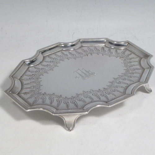 Antique Georgian sterling silver Neoclassical style teapot stand having a shaped rectangular body with a raised border, a hand-engraved ground with floral decoration, and sitting on four flange feet. Made by Henry Chawner of London in 1789. The dimensions of this fine hand-made silver teapot stand are length 16.5 cms (6.5 inches), width 12.5 cms (5 inches), and it weighs approx. 140g (4.5 troy ounces). Please note that this item is crested.
	   