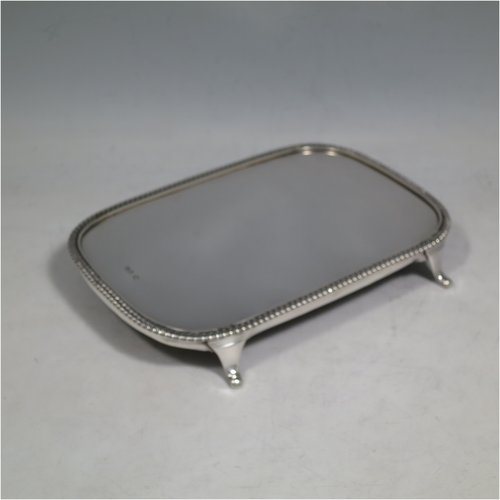 An Antique Georgian sterling silver teapot stand having a rectangular body with rounded corners, an applied gadroon border, a plain ground with wooden base, and sitting on four flange feet. Made in ca. 1810. The dimensions of this fine hand-made silver teapot stand are length 18 cms (7 inches), and width 12.5 cms (5 inches). Please note that this item only has a makers mark, a duty mark, and a sterling standard mark.   