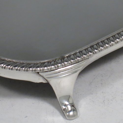 An Antique Georgian sterling silver teapot stand having a rectangular body with rounded corners, an applied gadroon border, a plain ground with wooden base, and sitting on four flange feet. Made in ca. 1810. The dimensions of this fine hand-made silver teapot stand are length 18 cms (7 inches), and width 12.5 cms (5 inches). Please note that this item only has a makers mark, a duty mark, and a sterling standard mark.   