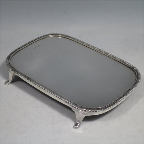 An Antique Georgian sterling silver teapot stand having a rectangular body with rounded corners, an applied gadroon border, a plain ground with wooden base, and sitting on four flange feet. Made in ca. 1810. The dimensions of this fine hand-made silver teapot stand are length 18 cms (7 inches), and width 12.5 cms (5 inches). Please note that this item only has a makers mark, a duty mark, and a sterling standard mark.   