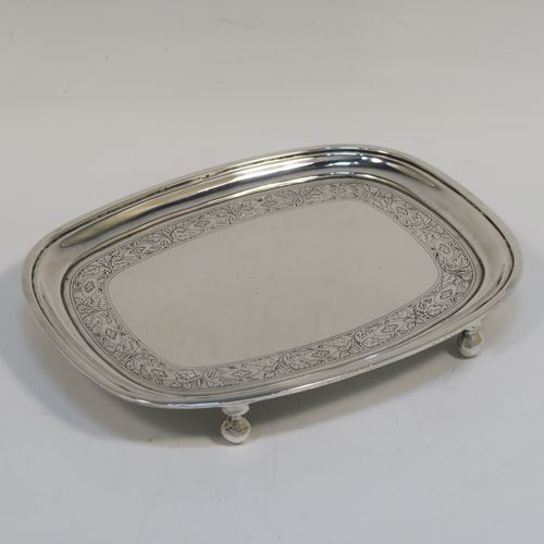 A very pretty Antique Georgian Sterling Silver teapot stand, having a rectangular body with rounded corners and a band of bright-cut hand-engraved floral decoration, a raised border with an applied reeded edge, and sitting on four ball feet. This elegant antique silver teapot stand was made by Soloman Hougham of London in 1804. The dimensions of this fine hand-made antique silver teapot stand are length 16 cms (6.3 inches), width 12.5 cms (5 inches), and it weighs approx. 153g (4.9 troy ounces).   