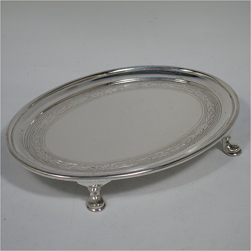 A very handsome Antique Edwardian Sterling Silver teapot stand, having an oval body with a band of hand-engraved floral decoration, a raised border with an applied reeded edge, and sitting on four cast hoof feet. Made by the Pairpoint Brothers of London in 1905. The dimensions of this fine hand-made antique silver teapot stand are length 17.5 cms (7 inches), width 13 cms (5 inches), and it weighs approx. 238g (7.8 troy ounces).    