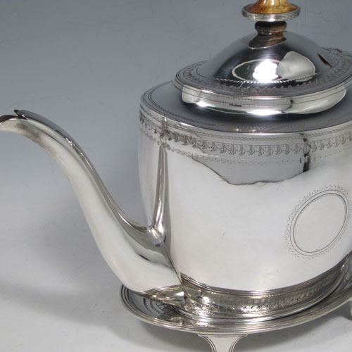 Antique Georgian sterling silver teapot on stand, having a hand-engraved oval body, with bands of floral decoration, a hinged domed lid with silver bound ivory finial, a wooden scroll handle, and sitting on its original stand with four flanged feet and reeded border. Made by Thomas Robins of London in 1800. The dimensions of this fine hand-made silver teapot on stand are length 28 cms (11 inches), height (on stand) 19 cms (7.5 inches), and it weighs approx. 543g (17.5 troy ounces).