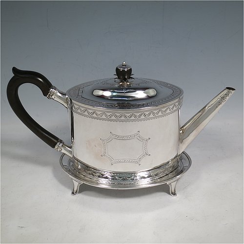 An Antique Georgian Sterling Silver teapot on stand, having a hand-engraved oval body, with bands of floral decoration, a hinged domed lid with silver bound wooden finial and flat hidden hinge, a wooden scroll handle, and sitting on its original stand with four flanged feet and reeded border. Made by Joseph Scammell of London in 1790. The dimensions of this fine hand-made antique silver teapot on stand are length 28 cms (11 inches), height (on stand) 16 cms (6.25 inches), and it weighs approx. 527g (17 troy ounces).   