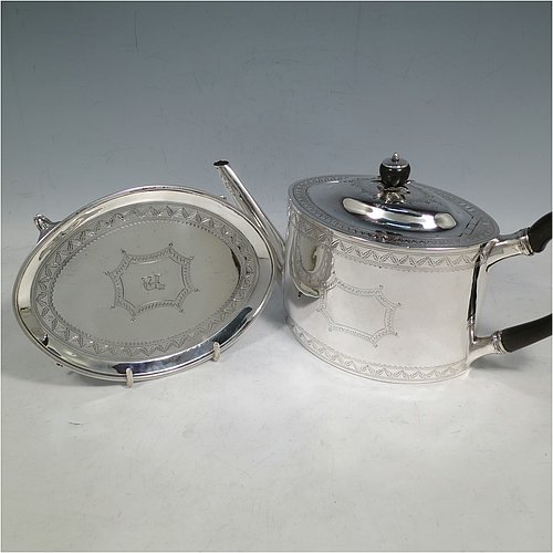 An Antique Georgian Sterling Silver teapot on stand, having a hand-engraved oval body, with bands of floral decoration, a hinged domed lid with silver bound wooden finial and flat hidden hinge, a wooden scroll handle, and sitting on its original stand with four flanged feet and reeded border. Made by Joseph Scammell of London in 1790. The dimensions of this fine hand-made antique silver teapot on stand are length 28 cms (11 inches), height (on stand) 16 cms (6.25 inches), and it weighs approx. 527g (17 troy ounces).   