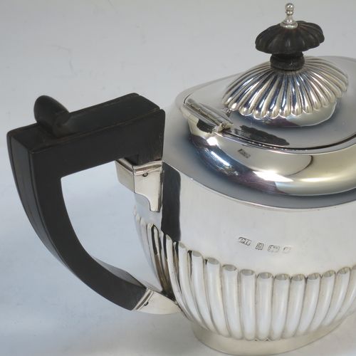 A handsome Antique Edwardian Sterling Silver teapot, having an oval body with hand-chased straight half fluting, a wooden insulated handle, a hinged domed lid with fluting, a wooden finial, and all sitting on a collet foot. Made by Charles Hornes of Birmingham in 1904. The dimensions of this fine hand-made antique silver bachelor teapot are height 13.5 cms (5.3 inches), length 23.5 cms (9.25 inches), and it weighs approx. 325g (10.5 troy ounces).  