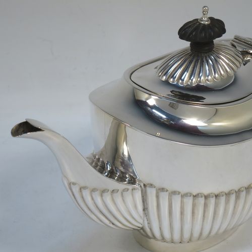 A handsome Antique Edwardian Sterling Silver teapot, having an oval body with hand-chased straight half fluting, a wooden insulated handle, a hinged domed lid with fluting, a wooden finial, and all sitting on a collet foot. Made by Charles Hornes of Birmingham in 1904. The dimensions of this fine hand-made antique silver bachelor teapot are height 13.5 cms (5.3 inches), length 23.5 cms (9.25 inches), and it weighs approx. 325g (10.5 troy ounces).  