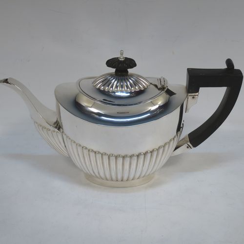 A handsome Antique Edwardian Sterling Silver teapot, having an oval body with hand-chased straight half fluting, a wooden insulated handle, a hinged domed lid with fluting, a wooden finial, and all sitting on a collet foot. Made by Charles Hornes of Birmingham in 1904. The dimensions of this fine hand-made antique silver bachelor teapot are height 13.5 cms (5.3 inches), length 23.5 cms (9.25 inches), and it weighs approx. 325g (10.5 troy ounces).  