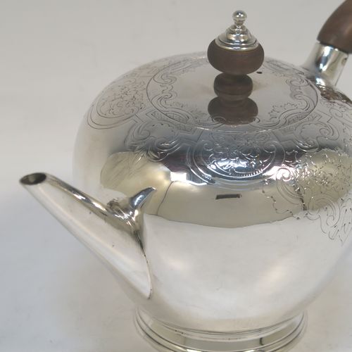 A very handsome Antique Georgian sterling silver teapot in an early George II Bullet style, having a  round bellied body with hand-chased scroll and floral decoration on the top, a straight tapering spout, a wooden scroll handle and finial, an invisibly hinged flat lid, and sitting on a collet foot. This elegant antique silver Bullet teapot was made by David Hennell I of London in 1749. The dimensions of this fine hand-made antique silver teapot are length 20 cms (8 inches), height 11 cms (4.3 inches), and it weighs approx. 350g (11.3 troy ounces).  