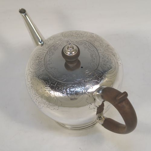 A very handsome Antique Georgian sterling silver teapot in an early George II Bullet style, having a  round bellied body with hand-chased scroll and floral decoration on the top, a straight tapering spout, a wooden scroll handle and finial, an invisibly hinged flat lid, and sitting on a collet foot. This elegant antique silver Bullet teapot was made by David Hennell I of London in 1749. The dimensions of this fine hand-made antique silver teapot are length 20 cms (8 inches), height 11 cms (4.3 inches), and it weighs approx. 350g (11.3 troy ounces).  