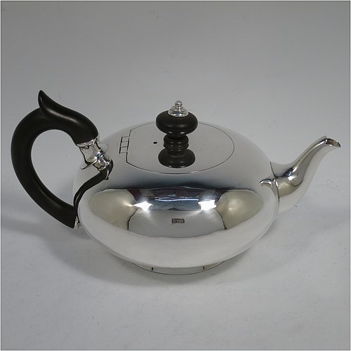 A rare Antique Georgian Sterling Silver bachelor size teapot, in a plain round bellied style, having a flat invisibly hinged lid with wooden finial, a wooden insulated handle, a plain curved spout, and all sitting on a collet foot. Made by William Edwards of London in 1824. The dimensions of this fine hand-made antique silver bachelor teapot are height 9.5 cms (3.75 inches), length 20 cms (8 inches), and it weighs approx. 350g (11.3 troy ounces).    