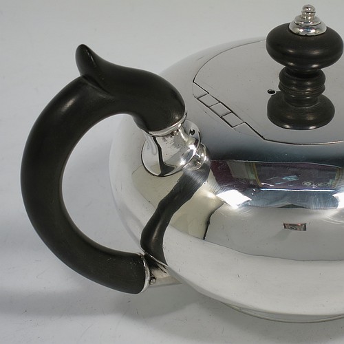 A rare Antique Georgian Sterling Silver bachelor size teapot, in a plain round bellied style, having a flat invisibly hinged lid with wooden finial, a wooden insulated handle, a plain curved spout, and all sitting on a collet foot. Made by William Edwards of London in 1824. The dimensions of this fine hand-made antique silver bachelor teapot are height 9.5 cms (3.75 inches), length 20 cms (8 inches), and it weighs approx. 350g (11.3 troy ounces).    