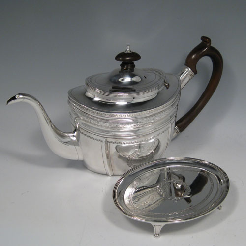 Antique Georgian sterling silver teapot on stand, having a hand-engraved oval body, a hinged domed lid with wooden finial, a wooden scroll handle, and sitting on its original stand with four flanged feet. Made by George Brasier of London in 1800. Length 29 cms (11.5 inches), height (on stand) 18 cms (7 inches). Weight approx. 527g (17 troy ounces).