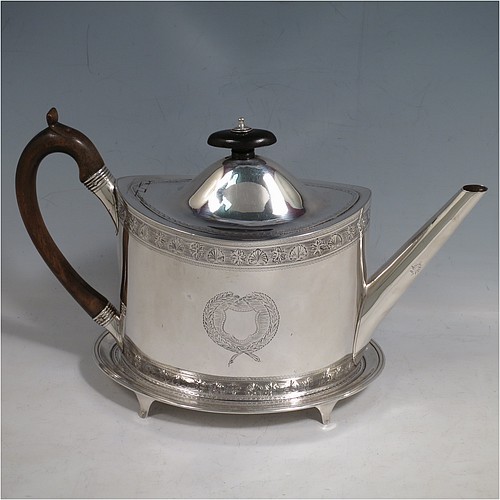 An Antique Georgian Sterling Silver teapot on stand, having a hand-engraved oval body, with bands of floral decoration, a hinged domed lid with wooden finial and flat hidden hinge, a wooden scroll handle, and sitting on a matching stand with four flanged feet and reeded border. The teapot made by Frances Purton of London in 1794, and the stand by Timothy Renou of London in 1795. The dimensions of this fine hand-made antique silver teapot on stand are length 26 cms (10.25 inches), height (on stand) 16 cms (6.25 inches), and it weighs approx. 475g (15.2 troy ounces).    